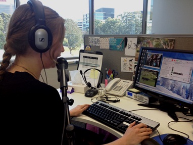 Woman using live captioning set-up with microphone, headphones and computer